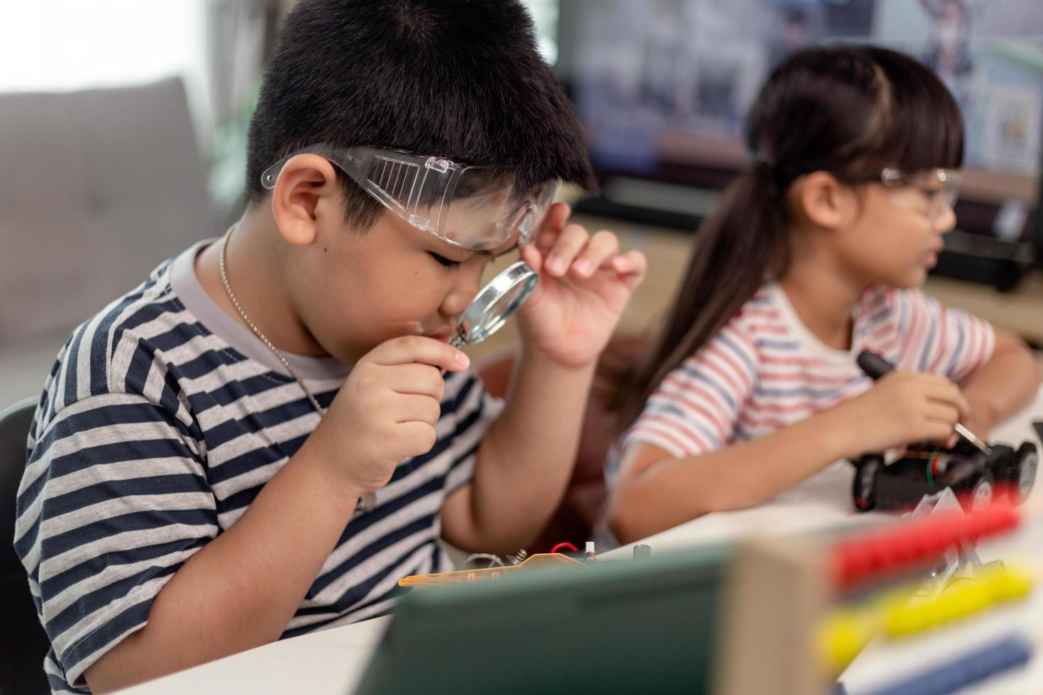 duas crianças asiáticas se divertindo aprendendo codificação juntas, aprendendo remotamente em casa, ciência da haste, educação escolar em casa, distanciamento social divertido, isolamento, novo conceito normal foto