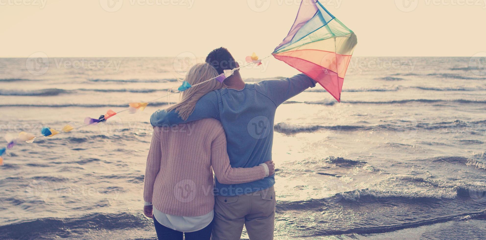 casal feliz se divertindo com pipa na praia foto