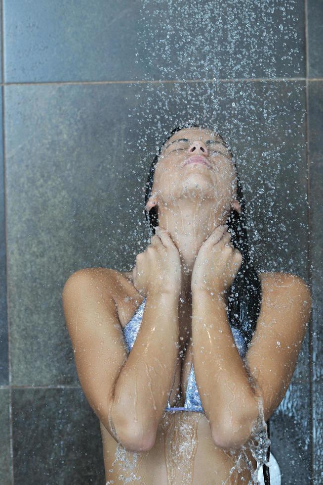 sexy jovem desfrutando de banho sob o chuveiro de água foto