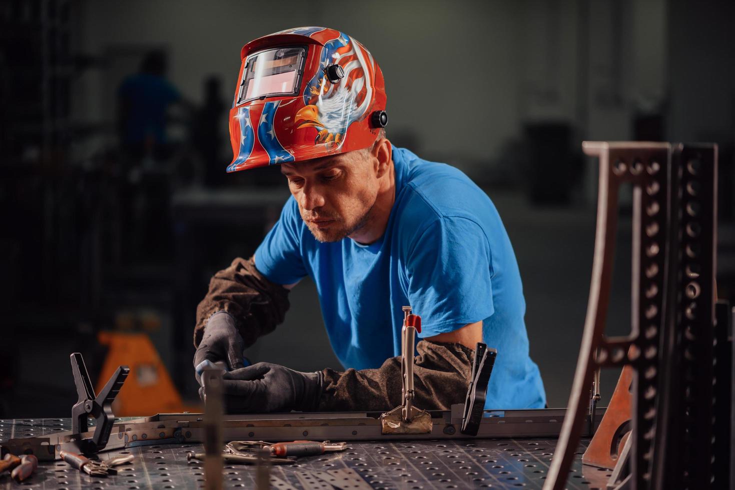 soldador profissional da indústria pesada trabalhando dentro da fábrica, usa capacete e começa a soldar. foco seletivo foto