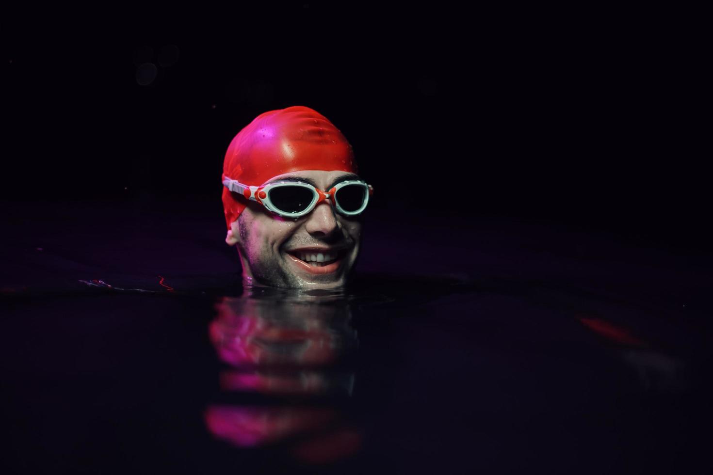 nadador de triatleta autêntico fazendo uma pausa durante o treinamento duro na luz de néon de gel noturno foto