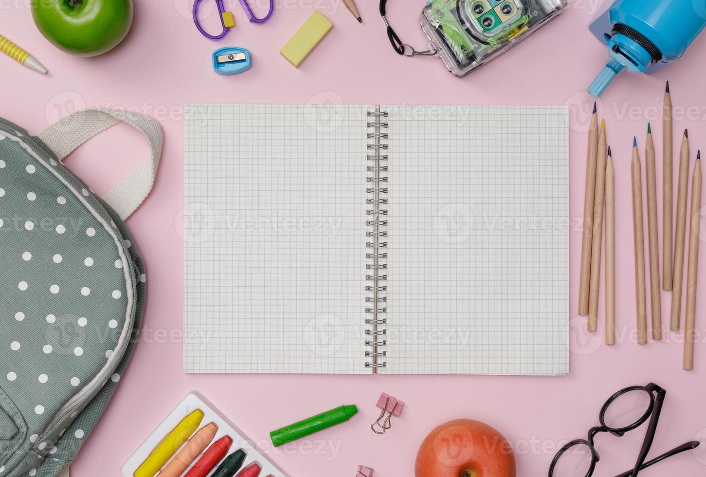 flatlay criativo de mesa de educação rosa com mochila, livros de estudante, sapatos, giz de cera colorido, óculos, espaço vazio isolado no fundo rosa, conceito de educação e volta às aulas foto