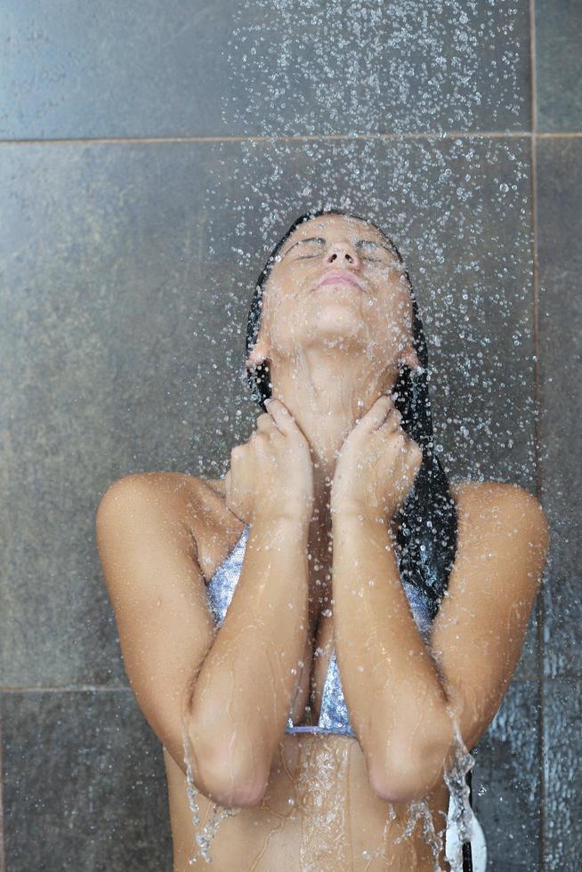 sexy jovem desfrutando de banho sob o chuveiro de água foto