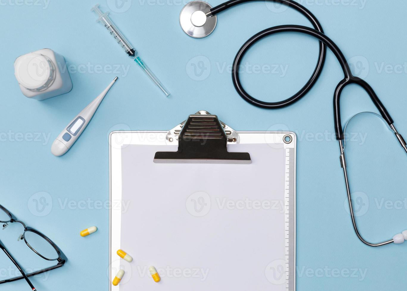 flatlay criativo de mesa azul de equipamento médico médico com estetoscópio, documentos médicos, termômetro, seringa e pílulas, conceito de cuidados de saúde, vista superior com espaço de cópia, isolado em azul foto