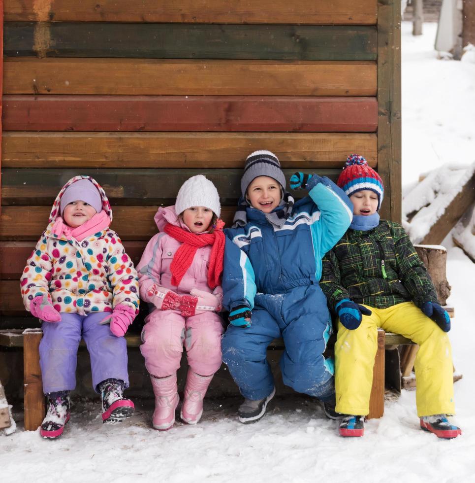 grupo de crianças sentados juntos em frente a cabana de madeira foto