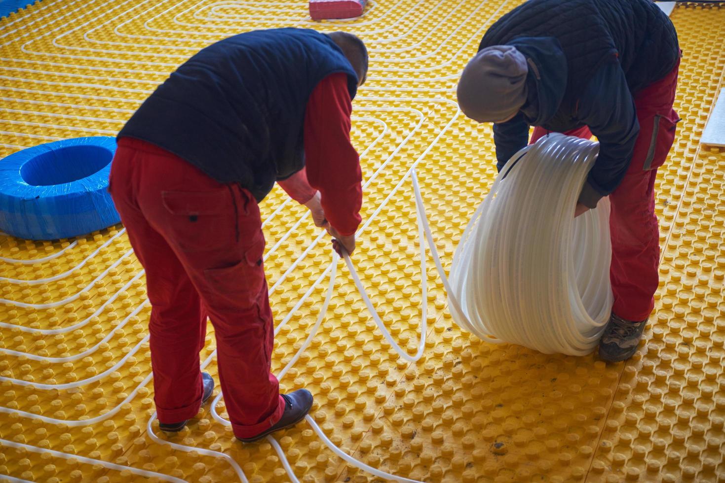 trabalhadores instalando sistema de piso radiante foto