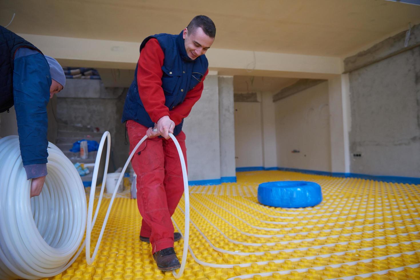 trabalhadores instalando sistema de piso radiante foto