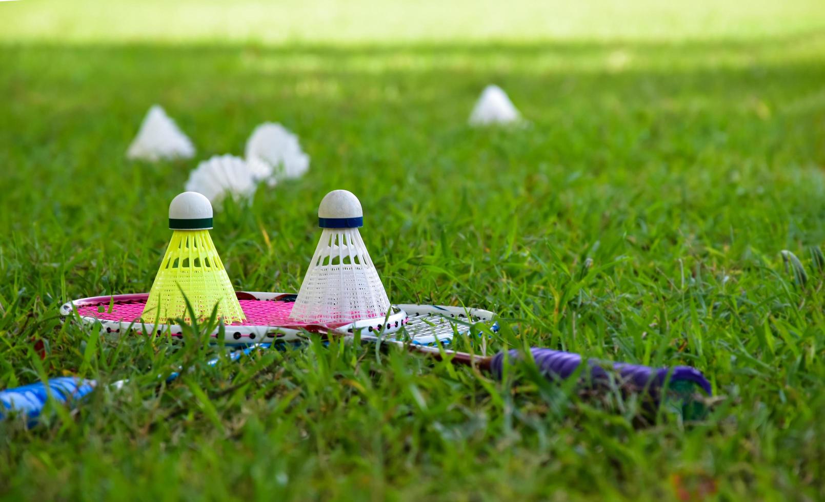 equipamentos de badminton ao ar livre petecas e raquetes de badminton, no gramado, foco suave e seletivo em petecas, conceito de jogo de badminton ao ar livre foto