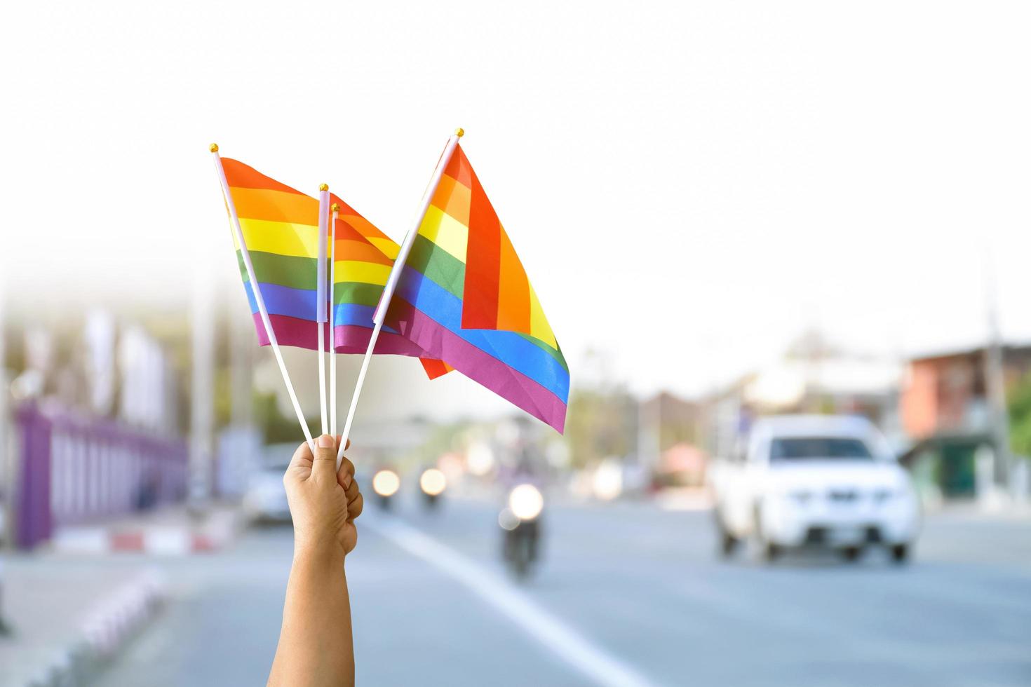 bandeiras do arco-íris segurando na mão ao lado do símbolo lgbtq da estrada rural, conceito para chamar e mostrar aos passageiros e motoristas para apoiar e respeitar as pessoas lgbtq no mês do orgulho em todo o mundo. foto