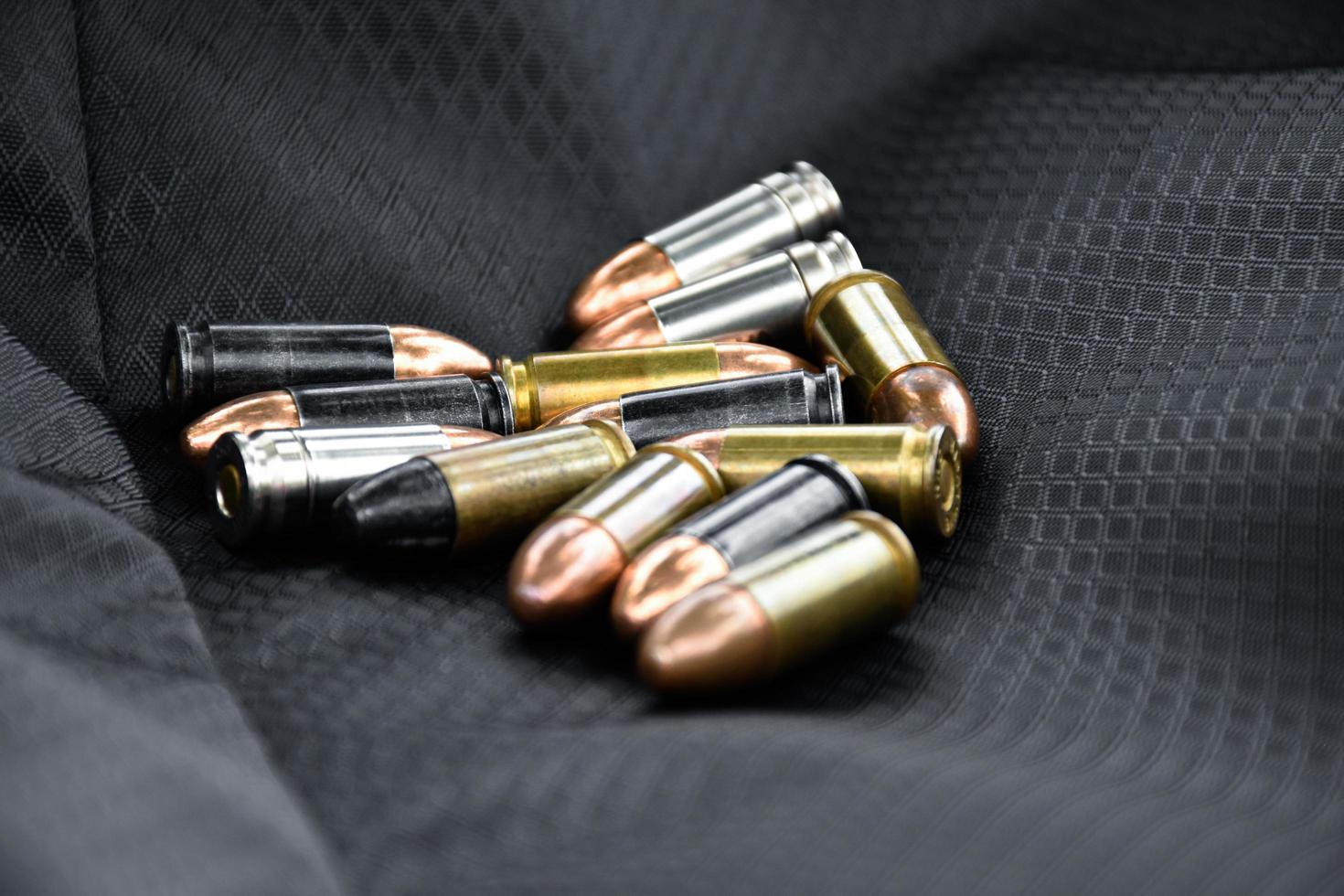 Balas de pistola de 9 mm e conchas de bala em fundo de couro preto, foco suave e seletivo. foto