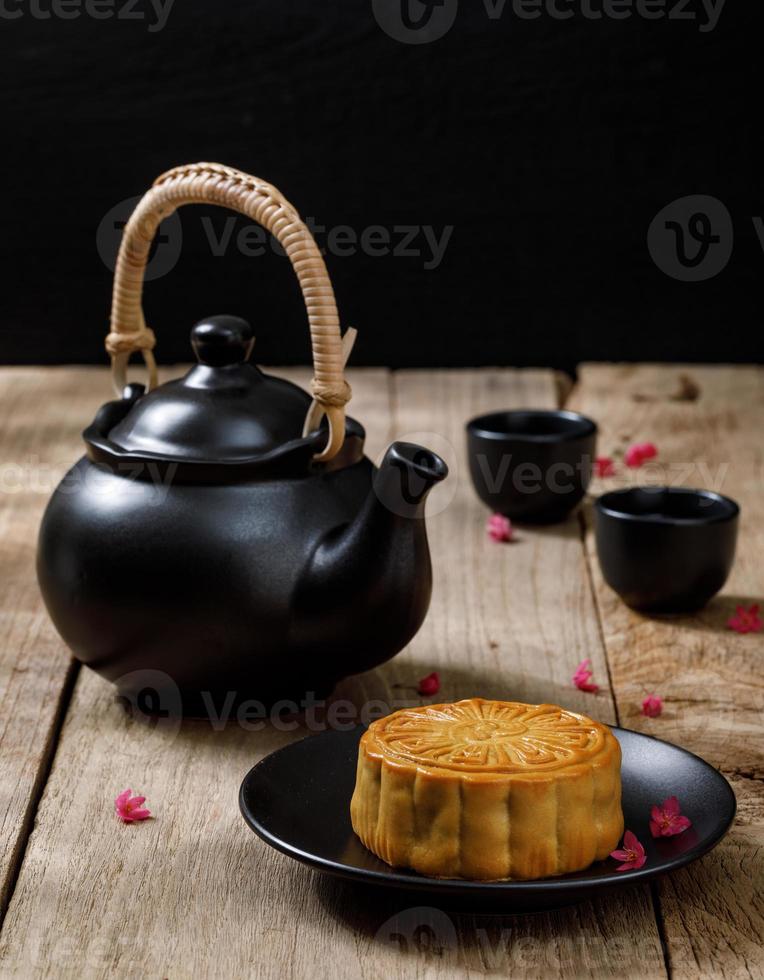 bolo de lua de comida deliciosa com uma xícara de chá quente no fundo da mesa de madeira com copyspace para o seu texto, conceito de festival tradicional chinês foto