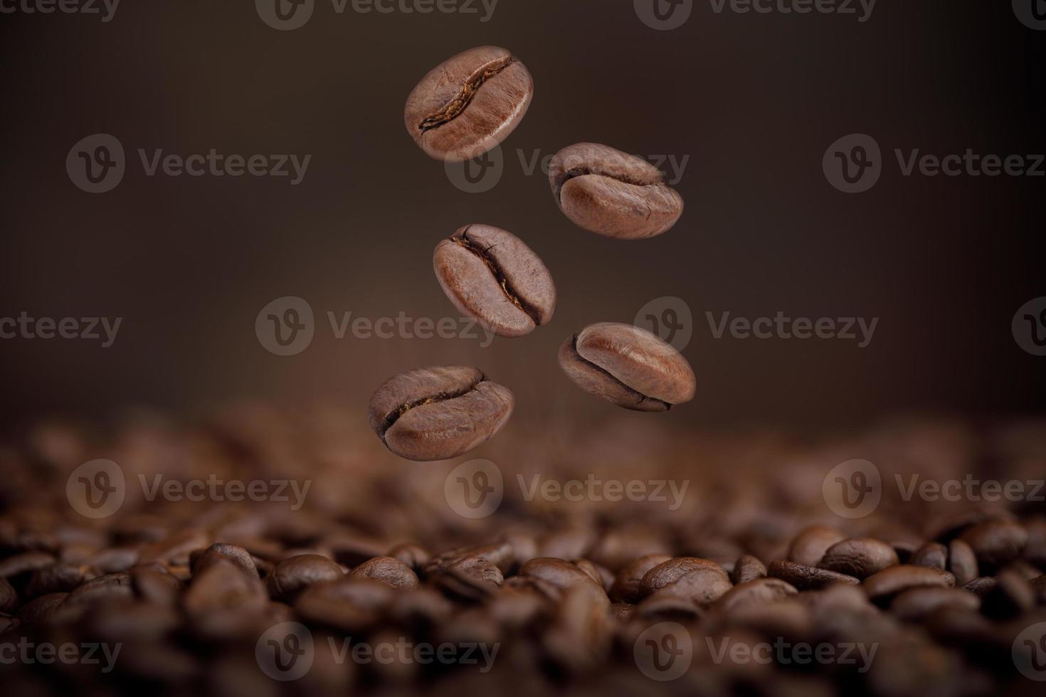 o calor dos grãos de café torrados castanhos caindo do ar no fundo marrom, produtos saudáveis pelo conceito de ingredientes naturais orgânicos foto
