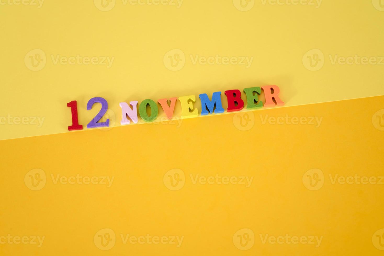12 de novembro em um fundo amarelo, papel com letras de madeira e multicoloridas com espaço para texto. foto