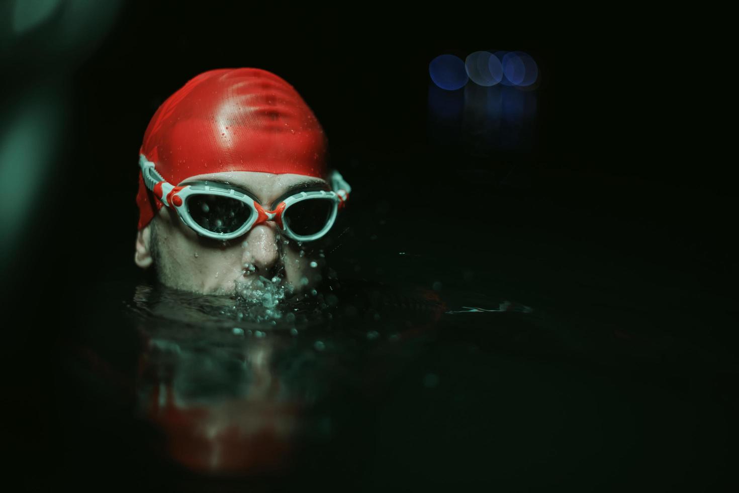 nadador de triatleta autêntico fazendo uma pausa durante o treinamento duro na luz de néon de gel noturno foto