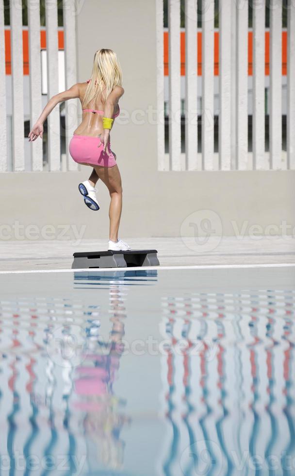 exercício de fitness mulher à beira da piscina foto