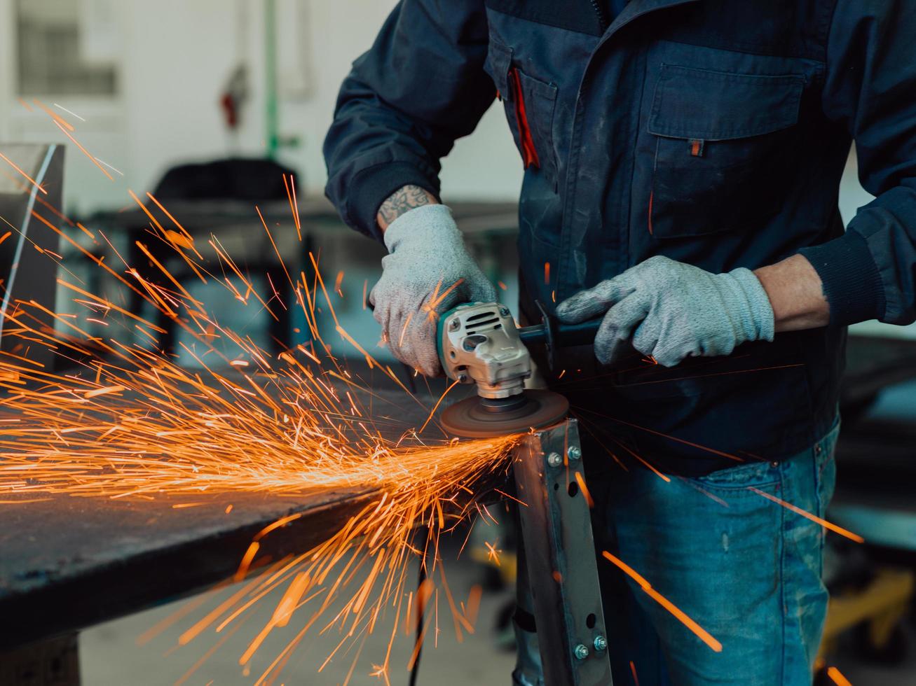 interior da fábrica de engenharia da indústria pesada com trabalhador industrial usando rebarbadora e cortando um tubo de metal. empreiteiro em uniformes de segurança e fabricação de capacetes de estruturas metálicas. foto