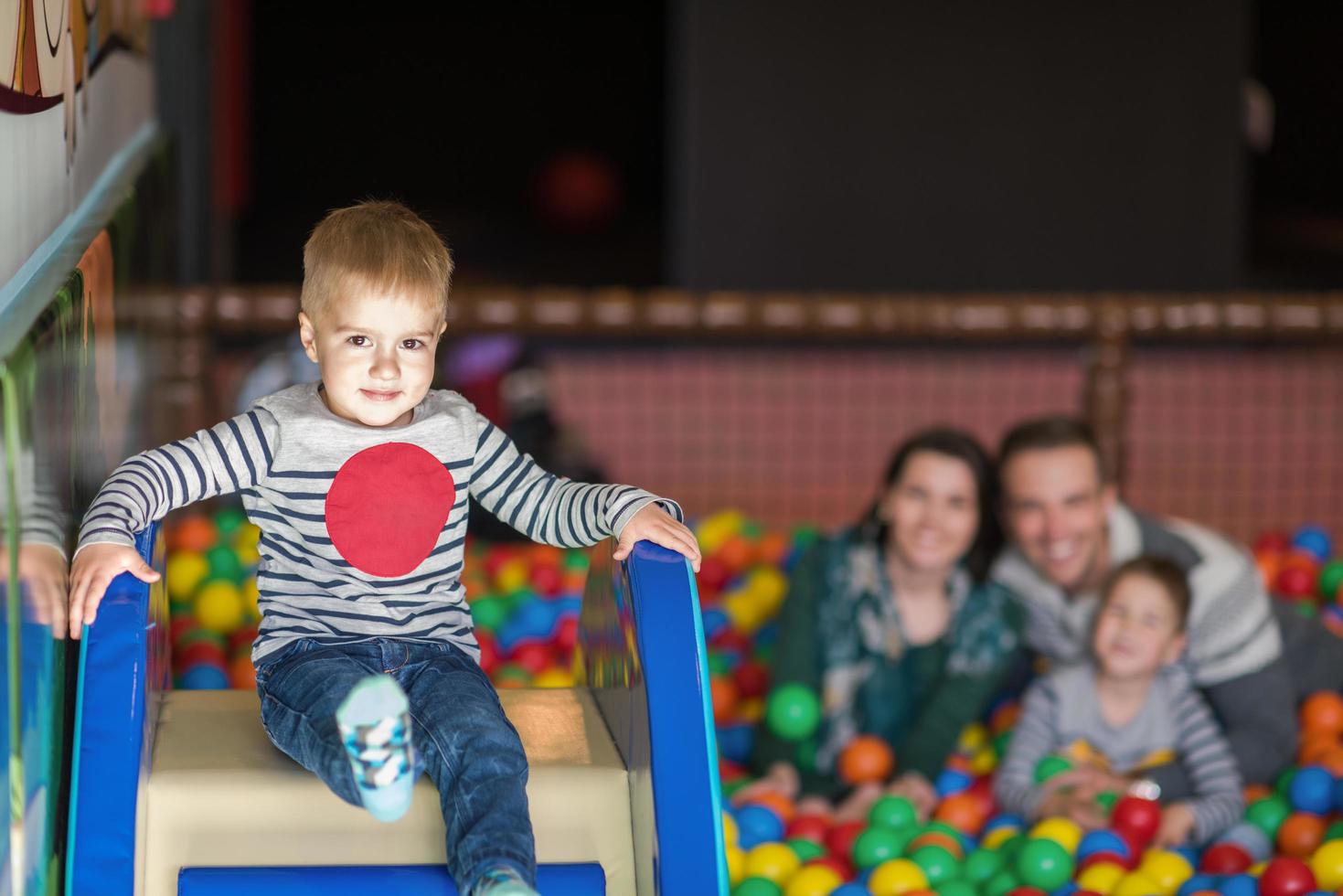 pais e filhos brincando na piscina com bolas coloridas foto