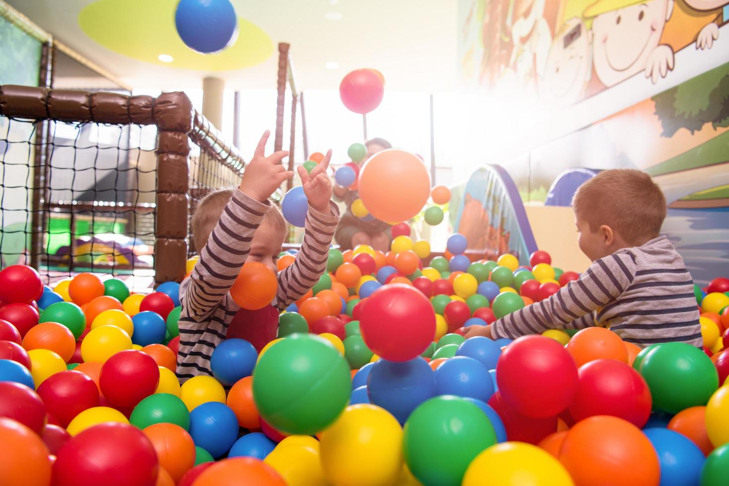 jovem mãe brincando com crianças na piscina com bolas coloridas foto