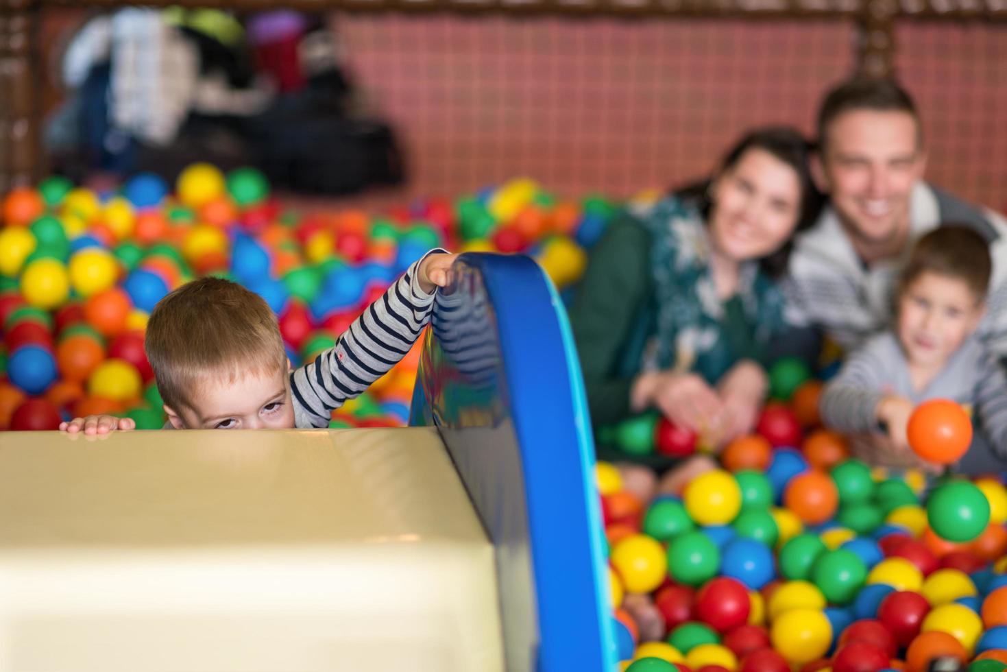 pais e filhos brincando na piscina com bolas coloridas foto