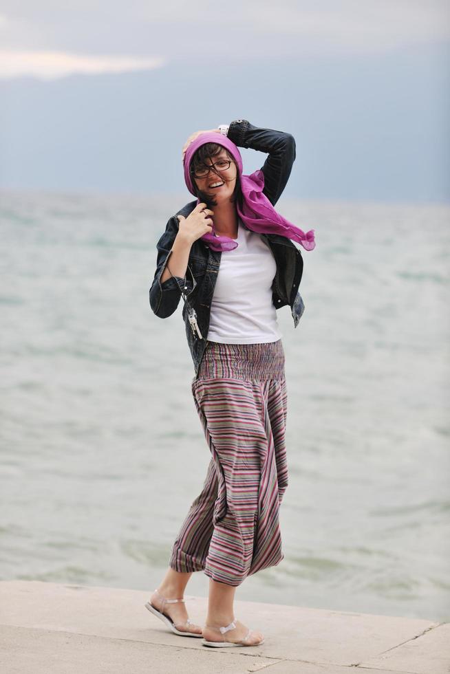 mulher jovem e bonita na praia com cachecol foto