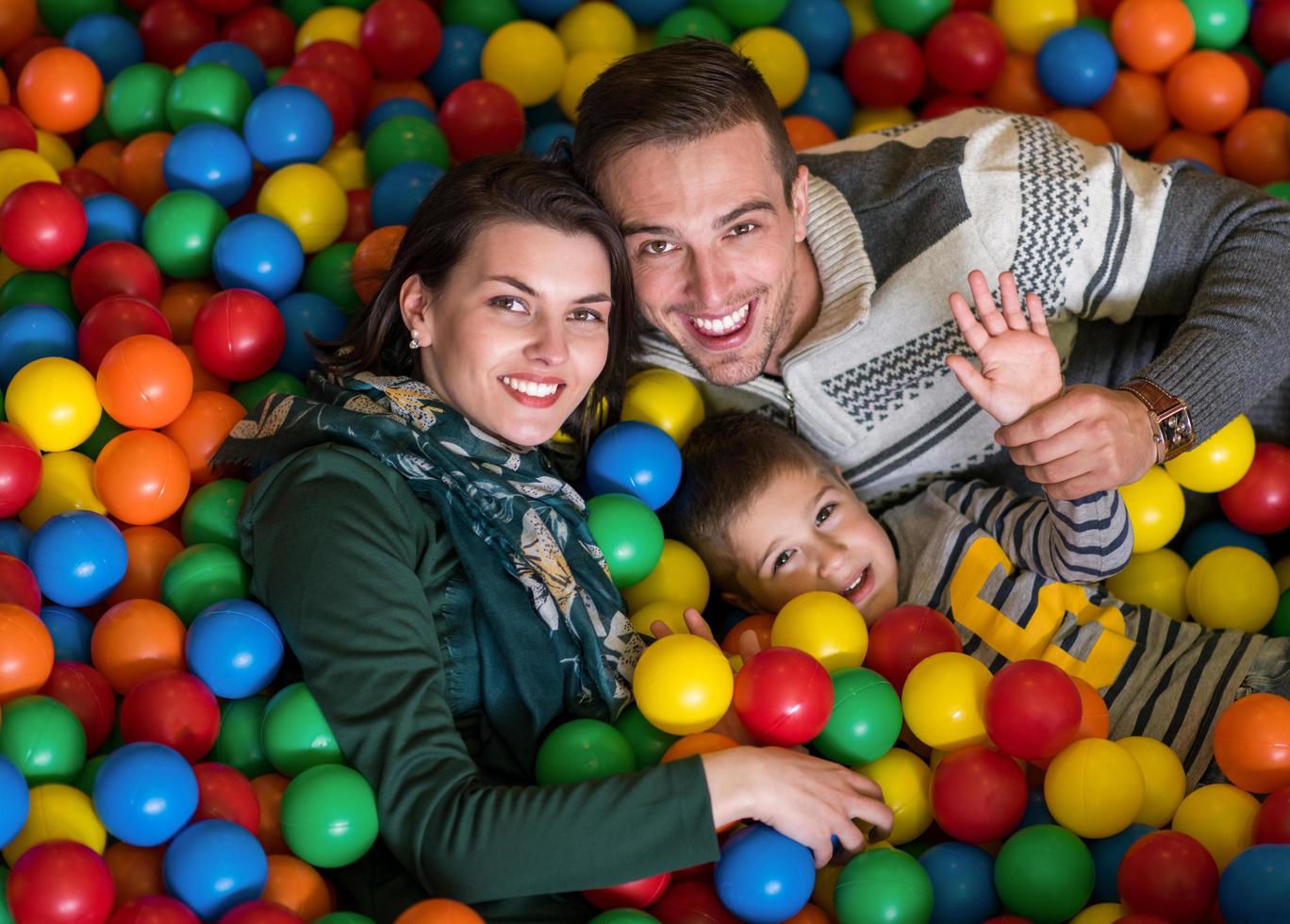 pais e filhos brincando na piscina com bolas coloridas foto