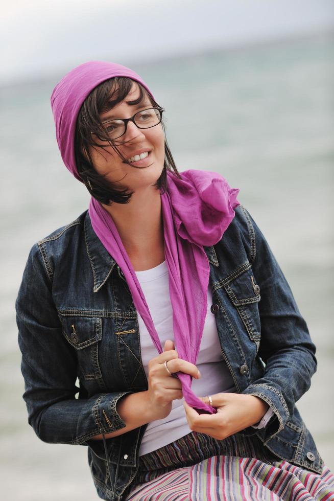 mulher jovem e bonita na praia com cachecol foto