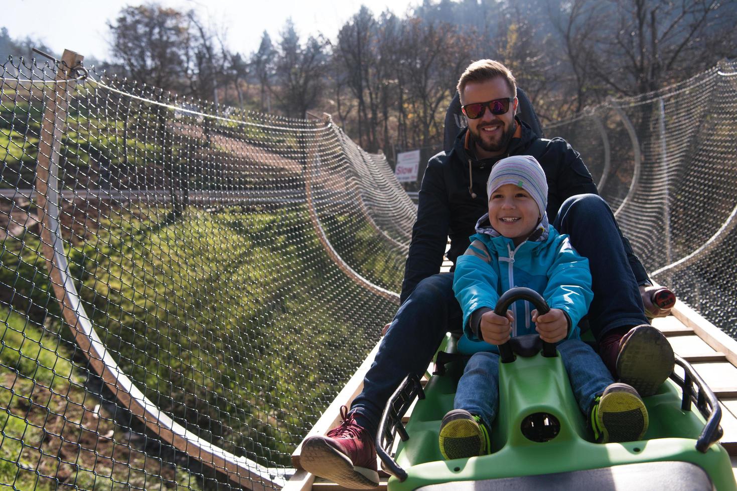 pai e filho gostam de dirigir na montanha-russa alpina foto