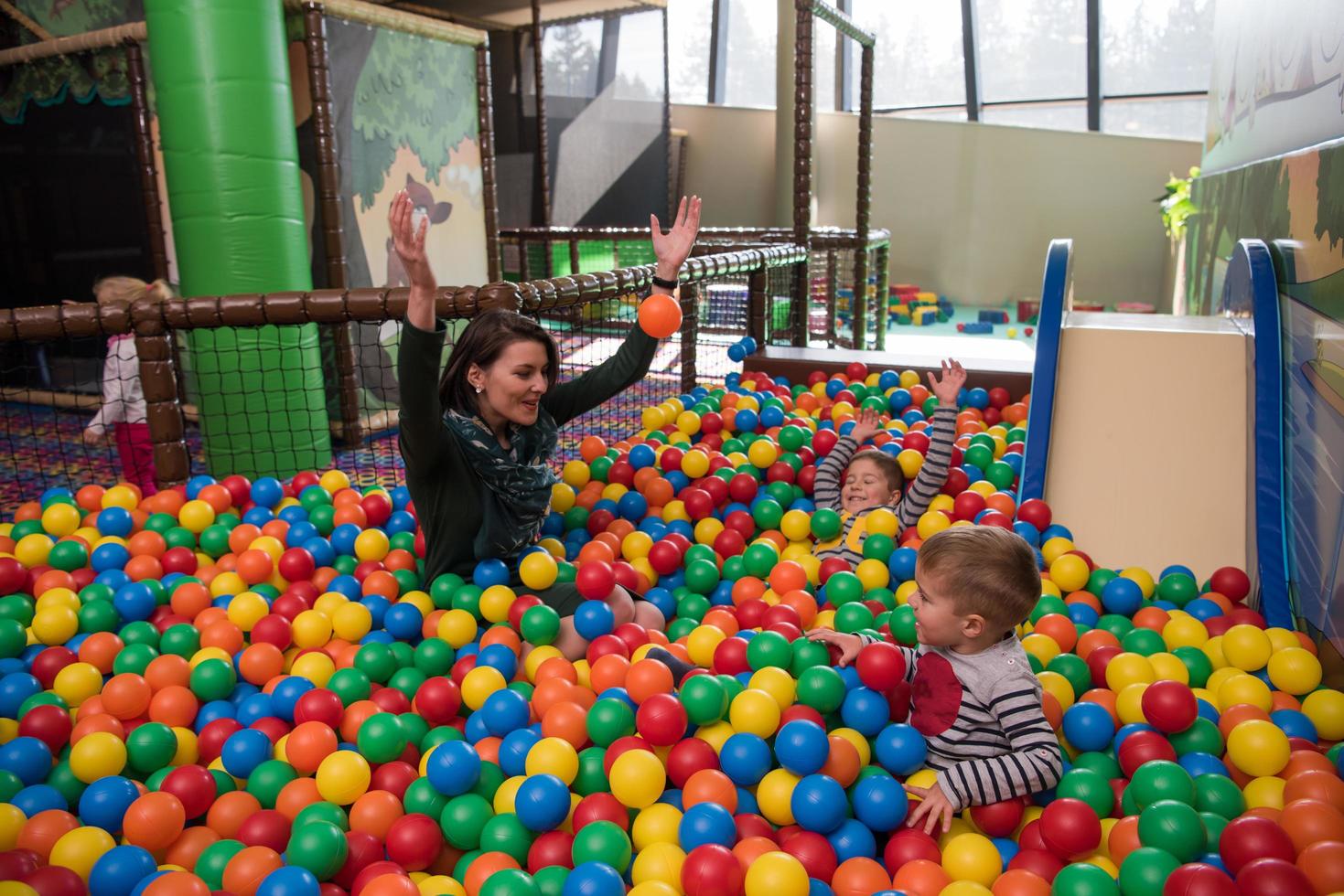 jovem mãe com seus filhos em uma sala de jogos infantil foto