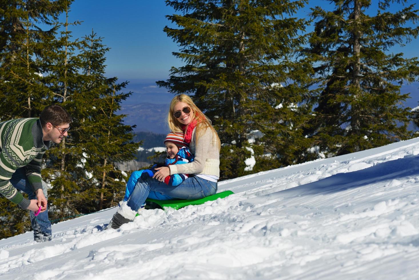 família se divertindo na neve fresca no inverno foto