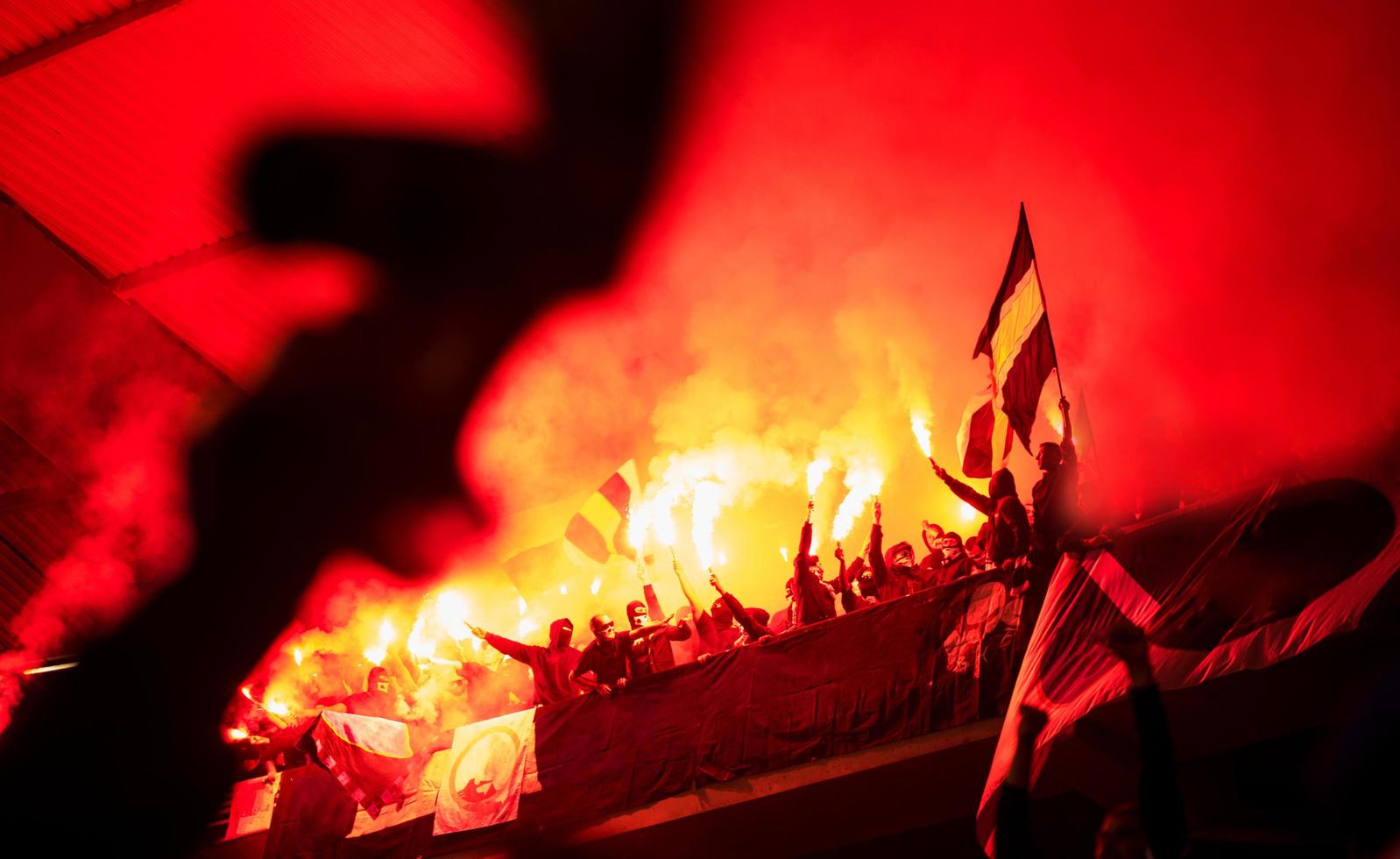 hooligans de futebol com máscara segurando tochas no fogo foto