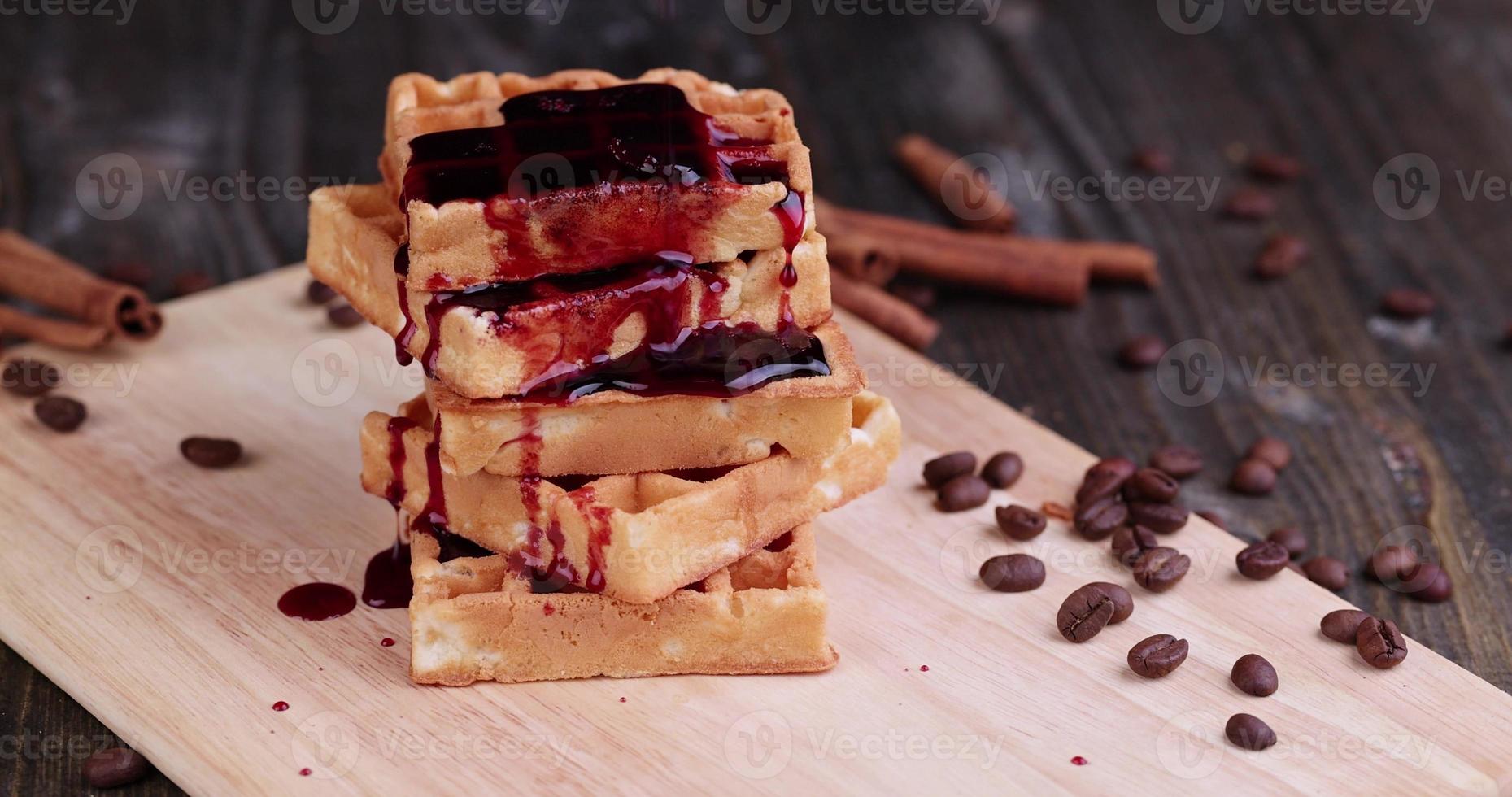 waffles macios despeje geléia de cereja vermelha em uma tábua de servir foto