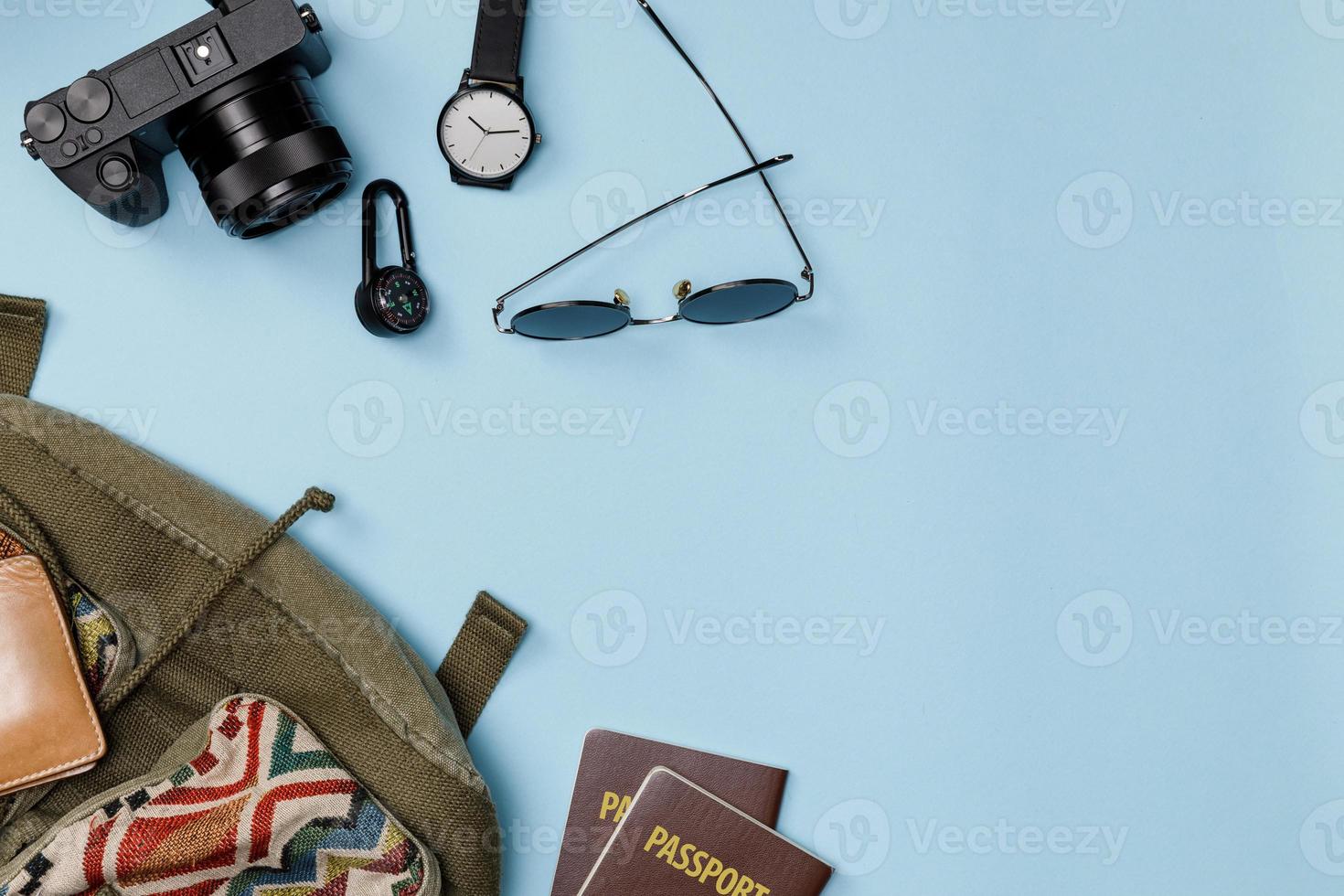 maquete de vista superior dos acessórios do viajante com passaporte, carteira, câmera, chapéu e mochila isolado fundo azul colorido com espaço vazio, conceito de viagens tropicais foto