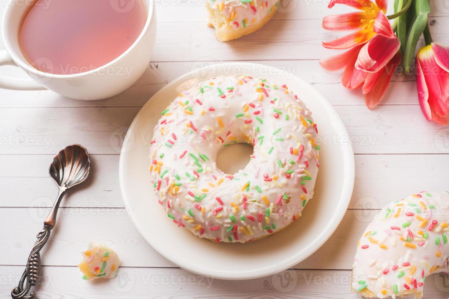 xícara de chá e donuts, tulipas de flores na mesa branca com espaço de cópia. foto