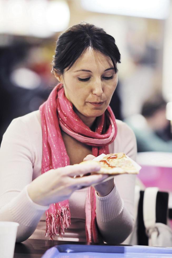 mulher come comida de pizza no restaurante foto