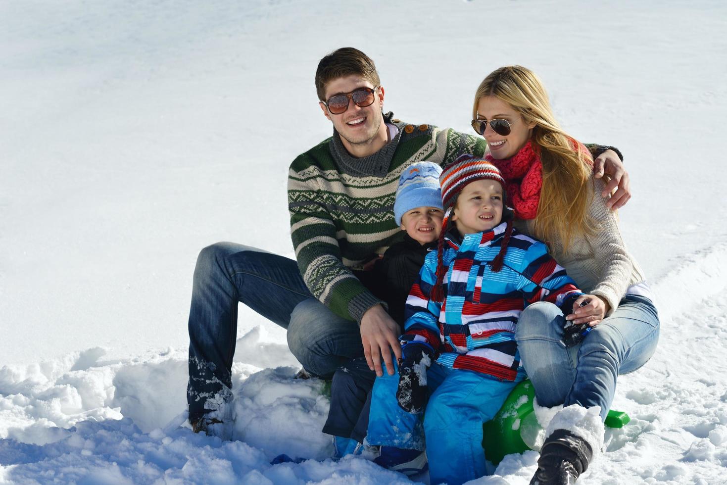 família se divertindo na neve fresca no inverno foto