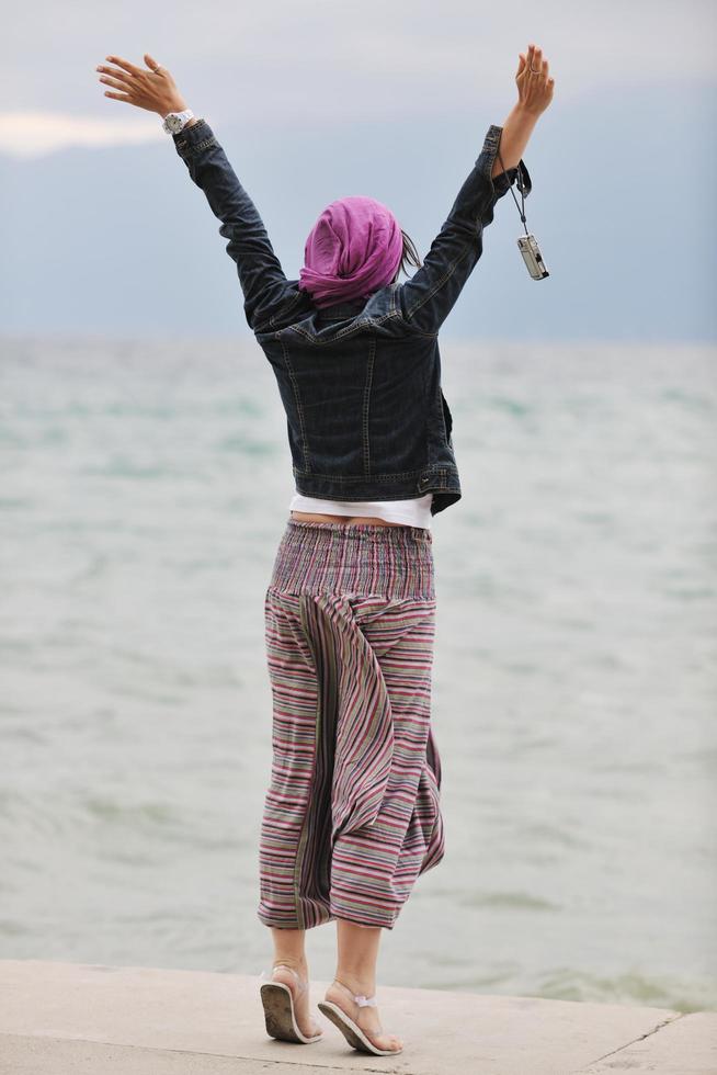 mulher jovem e bonita na praia com cachecol foto