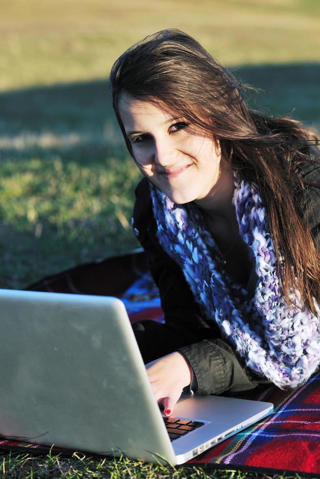 jovem adolescente trabalha no laptop ao ar livre foto