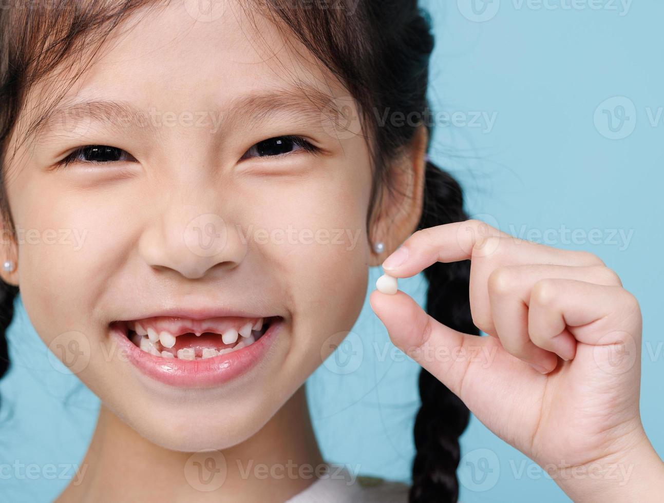 menina criança asiática sorrindo com dentes soltos, odontologia e conceito de cuidados de saúde foto