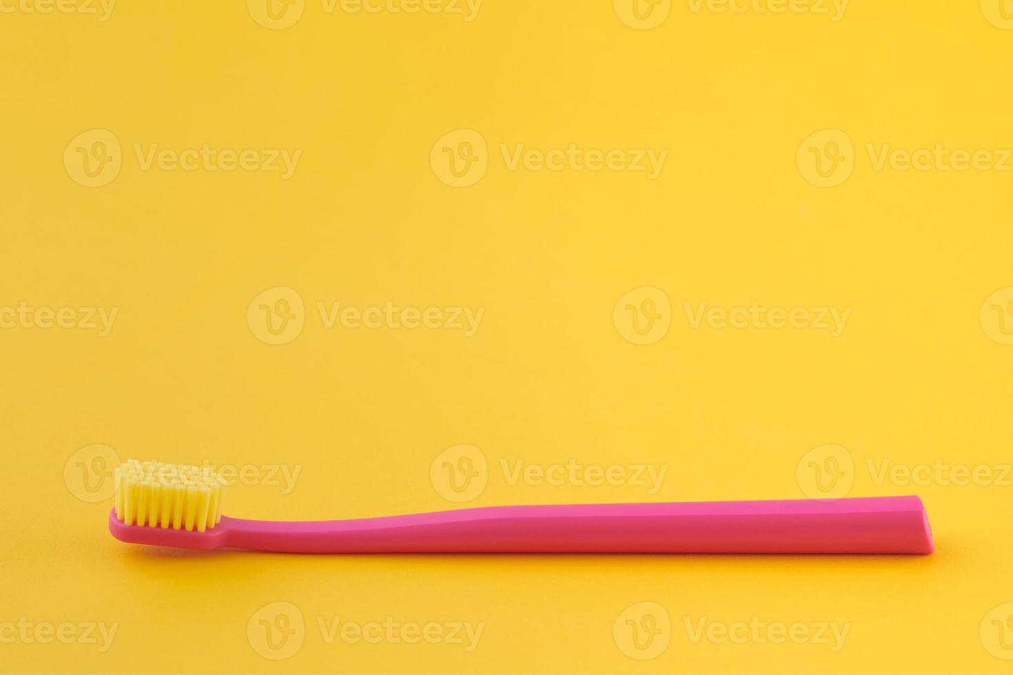 escova de dentes rosa em fundo amarelo para higiene bucal para limpar dentes, gengivas e língua foto