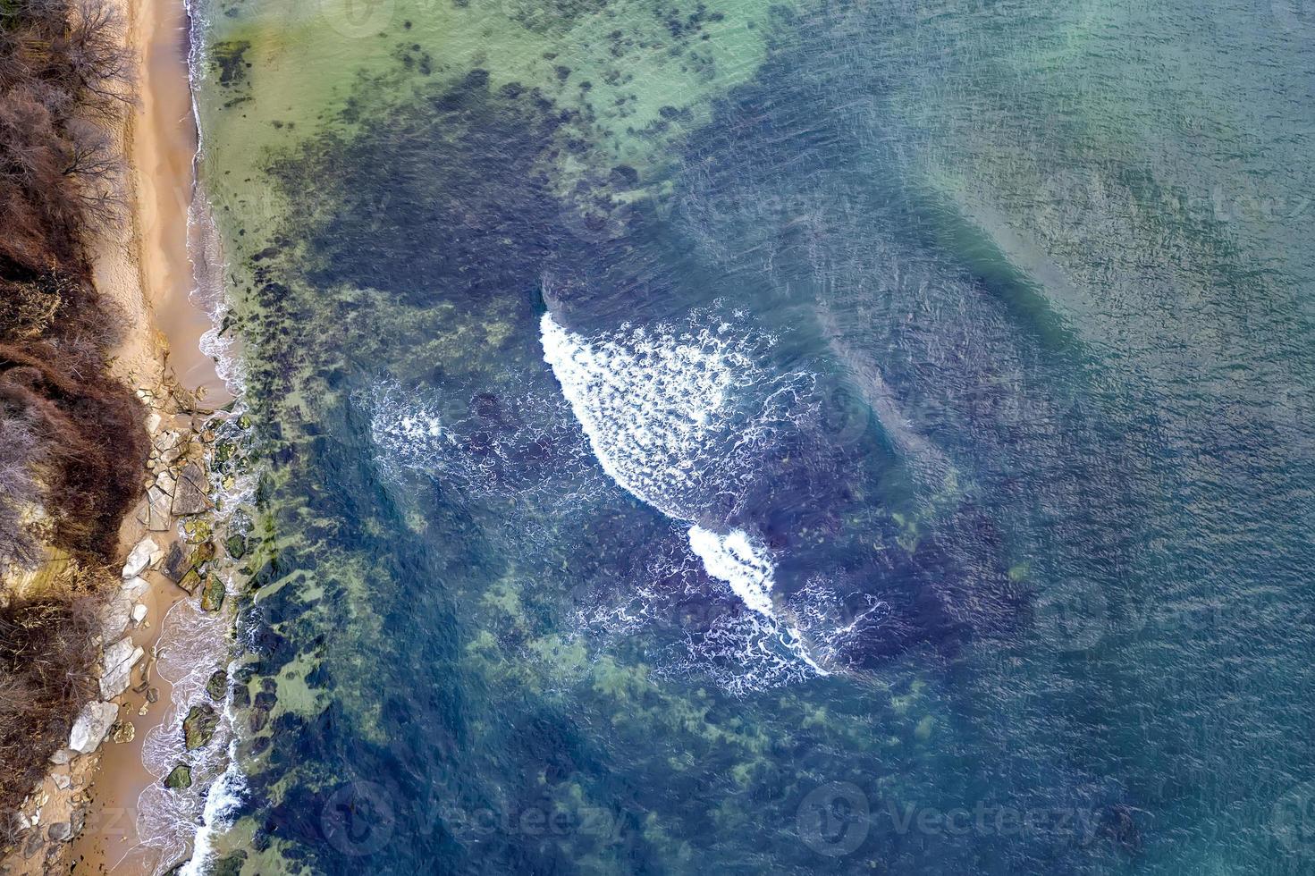 vista aérea de drone da superfície do litoral com ondas e pedras. vista do topo foto