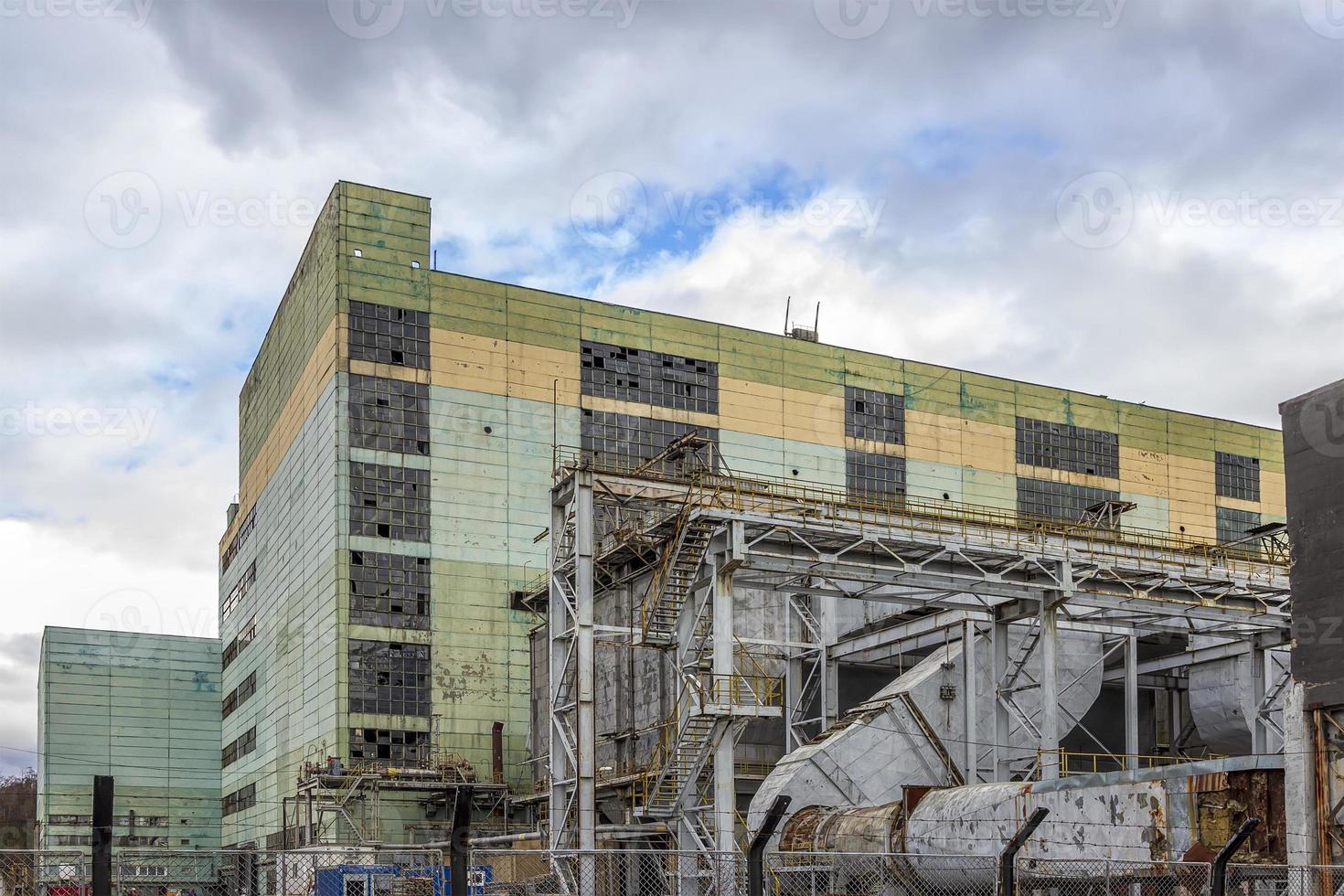 edifício de produção de vários andares atrás de uma cerca de arame. pitoresca antiga fábrica. objeto industrial envelhecido. foto