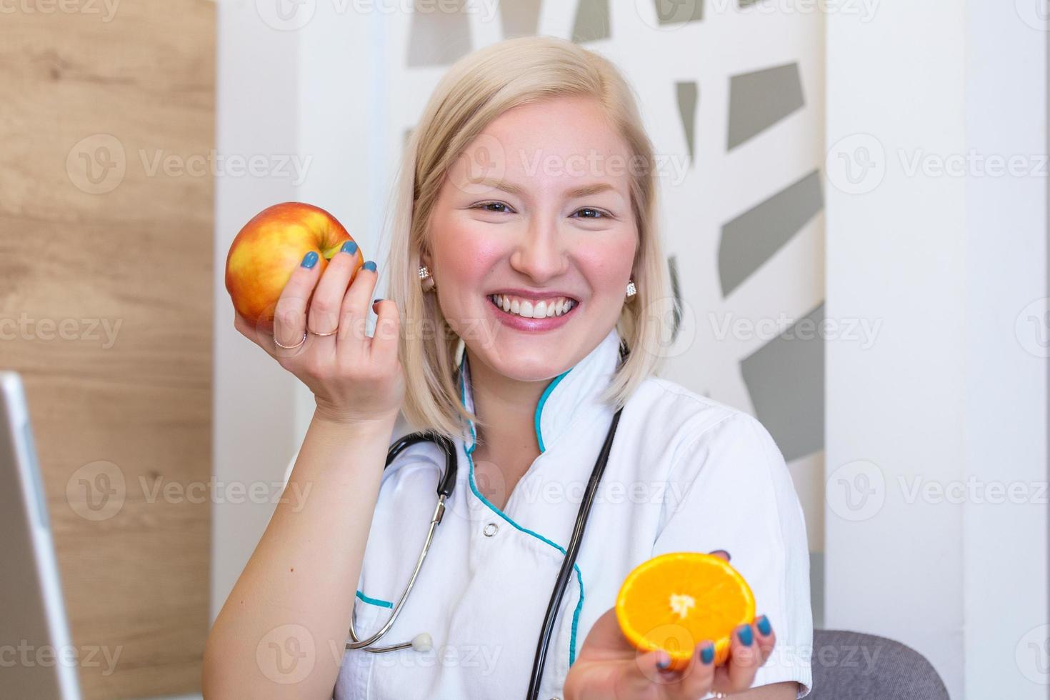 nutricionista sorridente em seu escritório, ela está mostrando vegetais e frutas saudáveis, conceito de saúde e dieta. nutricionista feminina com frutas trabalhando em sua mesa. foto