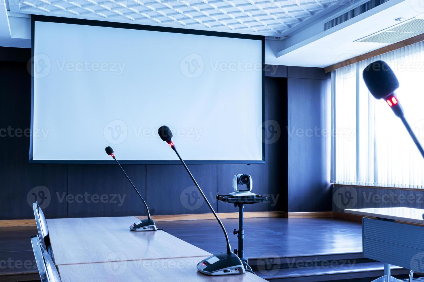 microfone na mesa com fundo de tela do projetor na sala de reuniões foto