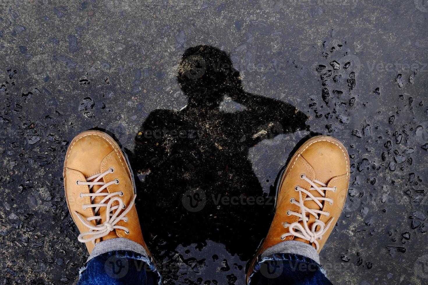 vista superior do fotógrafo tirando auto-retrato por sombra de reflexão no chão depois de parar de chover foto