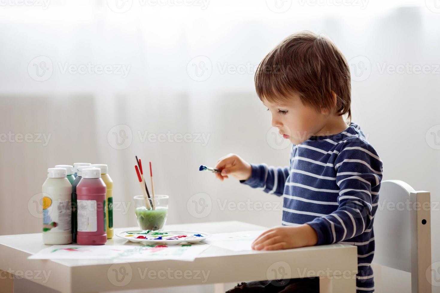 menino bonitinho pintando em seu álbum foto