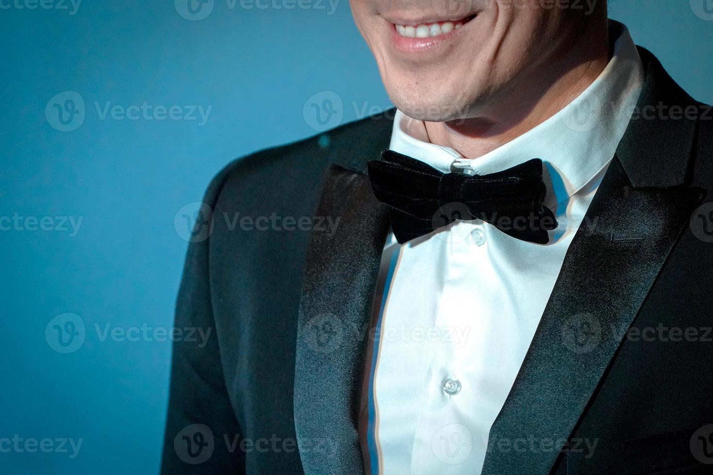 homem inteligente sorrindo em terno de táxi com gravata borboleta no fundo turquesa foto