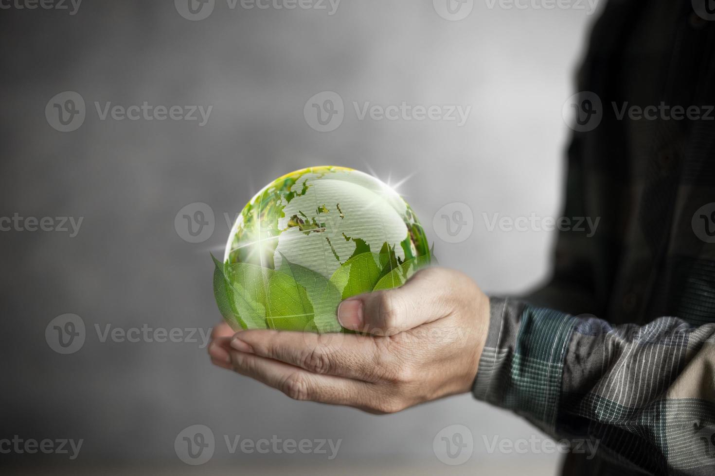 mão humana do dia da terra segurando um mundo verde apoiado por folhas, conservação e conceito de meio ambiente. foto