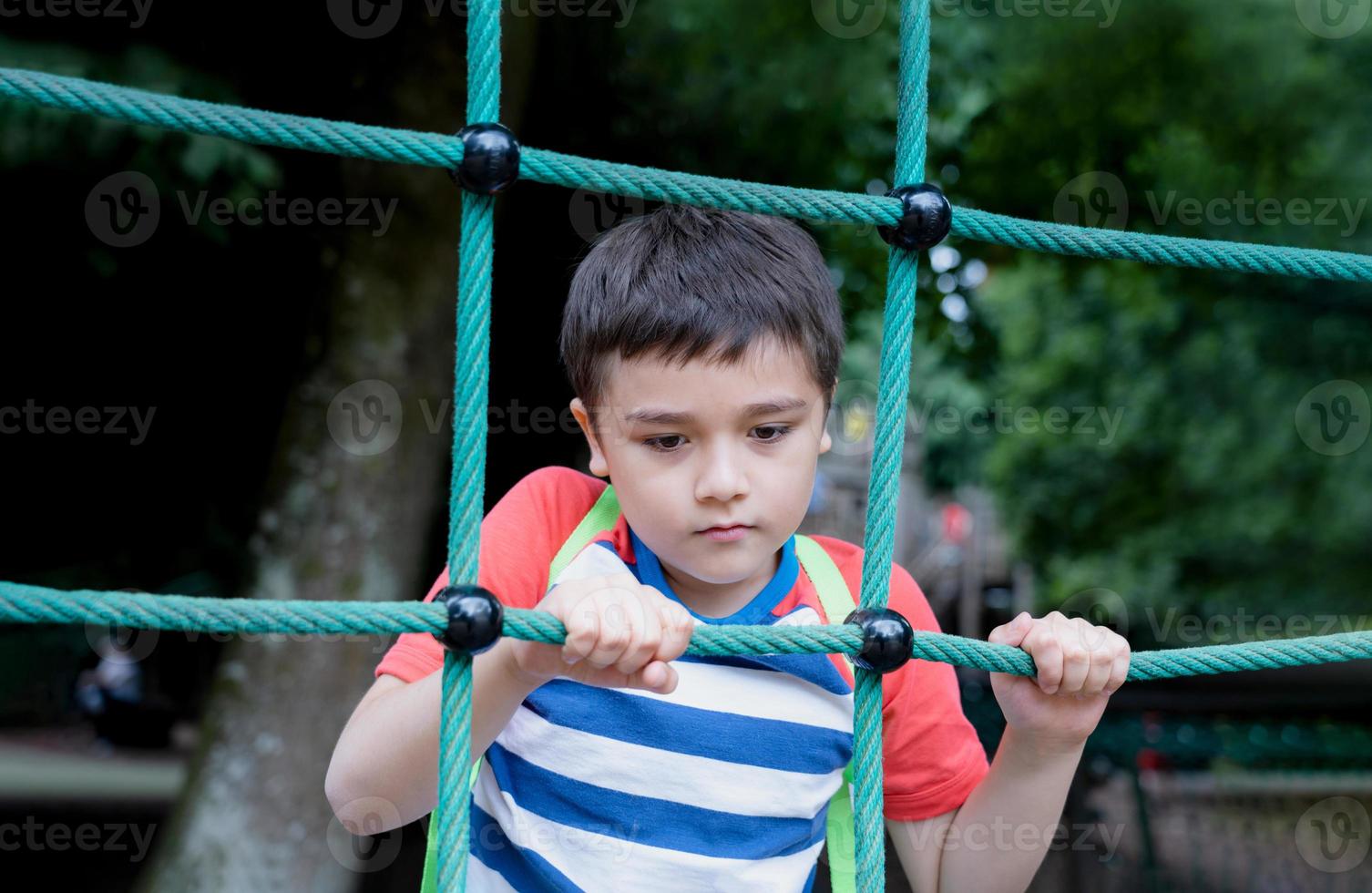 garoto de retrato segurando roupão no playground ao ar livre, parque de aventura de escalada infantil na primavera de dia ensolarado ou ssmmer, menino solitário jogando sozinho no parque público. foto