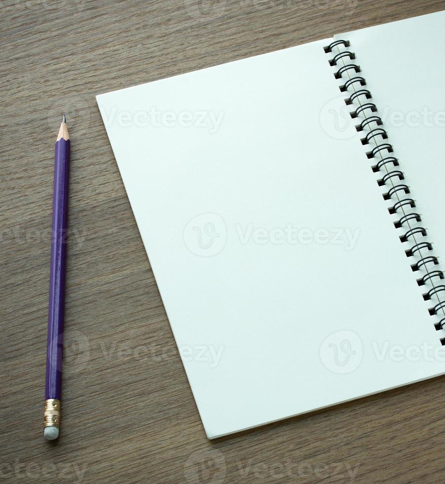 caderno espiral em branco e lápis sobre fundo escuro de madeira foto