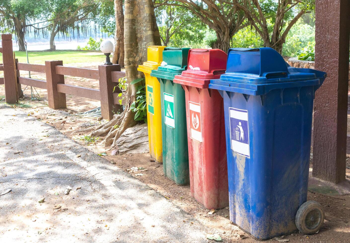 lata de lixo de cor amarela, verde, vermelha, azul na beira da estrada. foto